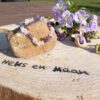 armband van ruwe amethist, rozenkwarts en bergkristal chips op een houten schijf met logo 'Heks en Maan', omringd door paarse bloemen en gedroogde planten