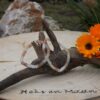 twee veelkleurige maansteen armbanden met chips kralen, hangend aan drijfhout op een houten schijf met logo 'Heks en Maan', naast oranje bloemen en stenen