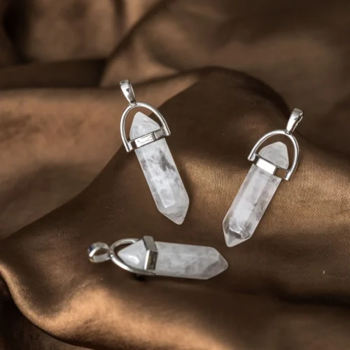drie puntvormige bergkristal hangers met zilverkleurige oogjes op bruine zijden stof