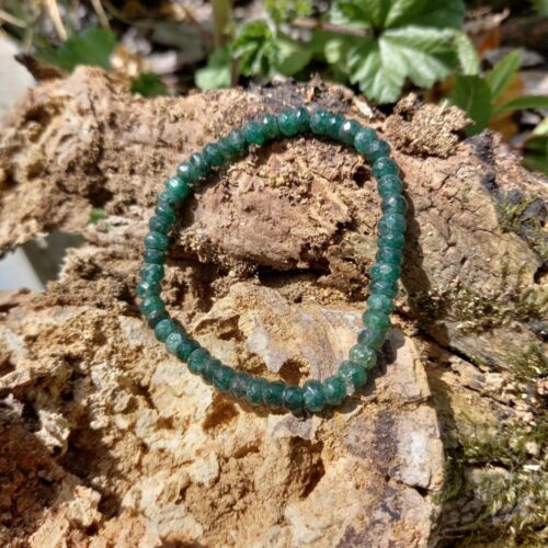 groene aventurijn kralen armband liggend op een stuk ruw boombast in de zon